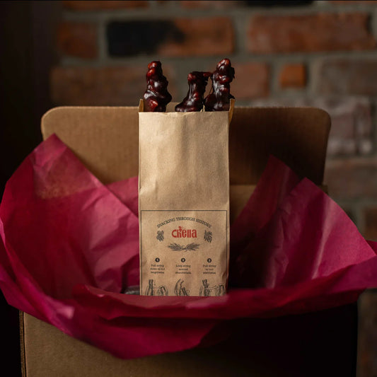 A photo of a bag of churchkhela that is in a shipping box with burgundy wrapping paper