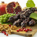 a photo of churchkhela being laid out on a wooden board with an opened pomegranate and walnuts with grapes on the board as well!