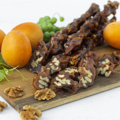 An image of Churchkhela after being cut up into smaller slices with apricots and walnuts in the background.
