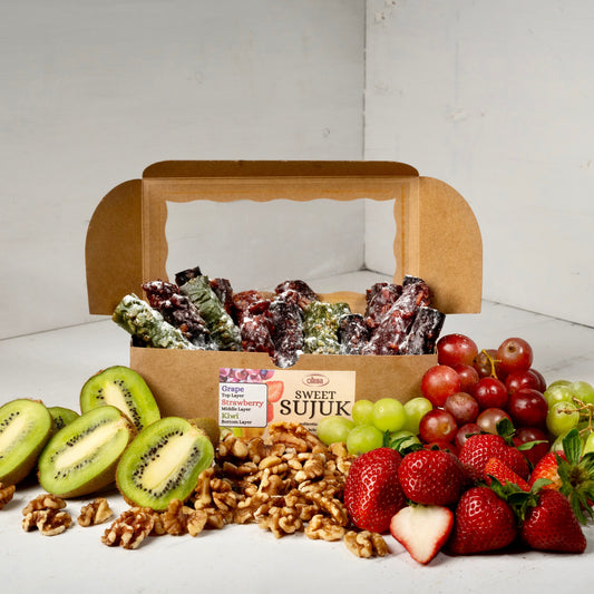 A photo of our Sweet Sujuk in a box with kiwis, walnuts, strawberries and grapes layed out in front of the box, helping to show what flavours we carry.